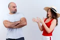 adult couple frowning man standing with closed posture impressed woman wearing hat spreading hands both looking each other jpg