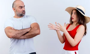 adult couple frowning man standing with closed posture impressed woman wearing hat spreading hands both looking each other jpg