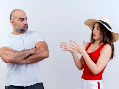 adult couple frowning man standing with closed posture impressed woman wearing hat spreading hands both looking each other jpg