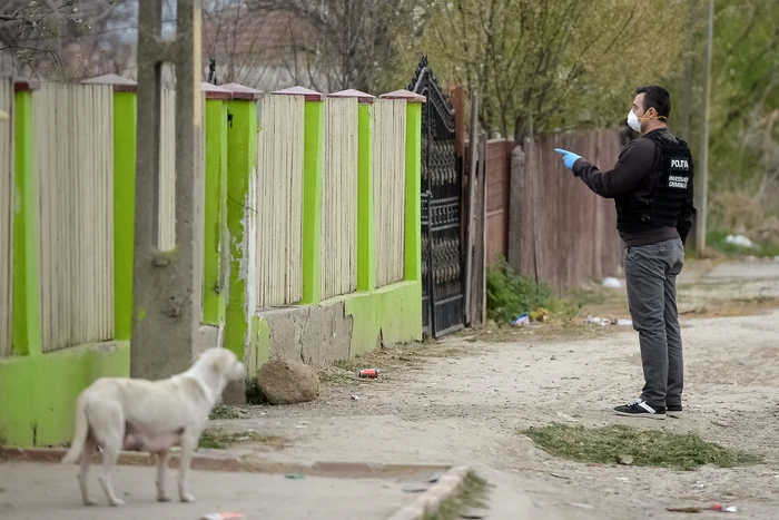 Un polițist atenționează o persoană aflată în spatele gardului