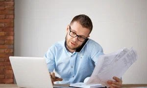 serious professional businessman talking phone with customer holding papers hand jpg