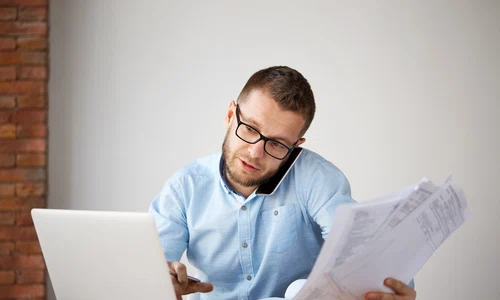 serious professional businessman talking phone with customer holding papers hand jpg