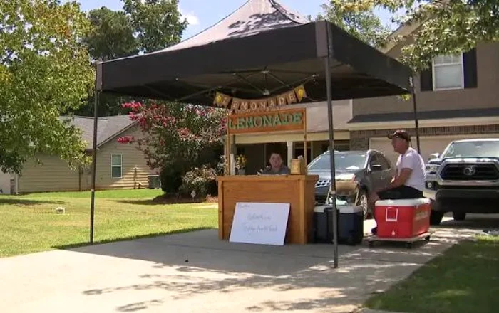 Băiatul vinde limonadă în cartierul său