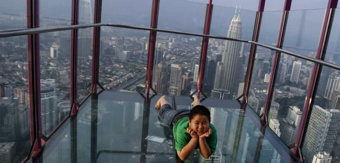 Un băiat pozează pentru o fotografie suvenir cu turnurile gemene Petronas aflate în spate dintr-un observatory de sticlă în Kuala Lumpur Tower din Kuala Lumpur Malaezia FOTO AP