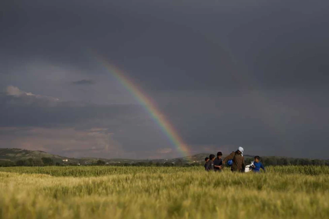 Refugiaţii sirieni merg pe câmpuri în faţa unui curcubeu la punctul de frontieră din Idomeni Grecia FOTO AP