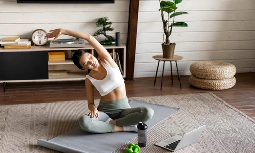 young asian fitness girl doing stretching sport workout home stretch arms looking laptop f(1) jpg