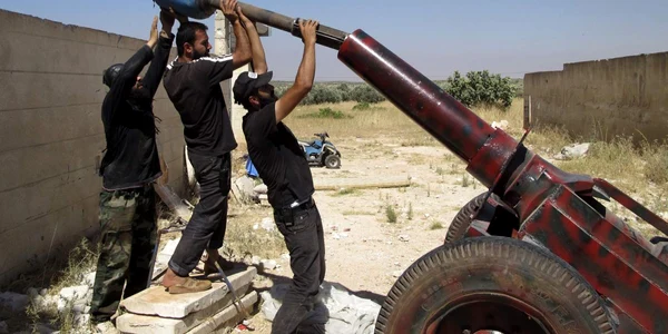 Luptători din Armata Siriană Liberă se pregătesc să lanseze un proiectil de artilerie în Idlib