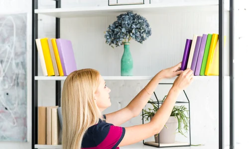 woman choosing book from shelf home jpg