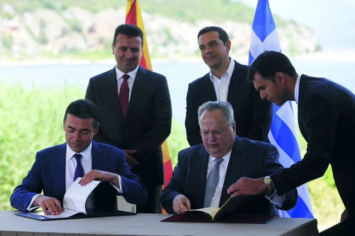 Ministrul grec de Externe Nikos Kotzias (dreapta, la masă) și omologul său macedonean Nikola Dimitrov semnează Acordul de la Prespa, sub privirile prim-ministrului grec Alexis Tsipras (dreapta, sus) și ale premierului macedonean Zoran Zaev (foto: Get