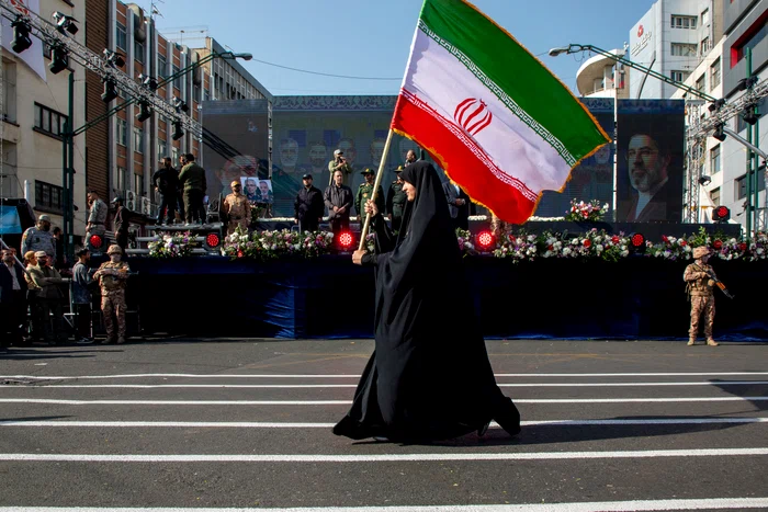 O femeie poartă un steag iranian în timpul unei demonstrații pro-guvernamentale. FOTO: Getty Images