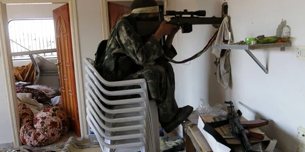 Un luptător rebel sta pe scaune în timp ce ţinteşte printr-o gaură într-o casă în oraşul Morek provincia Hama Siria FOTO Reuters