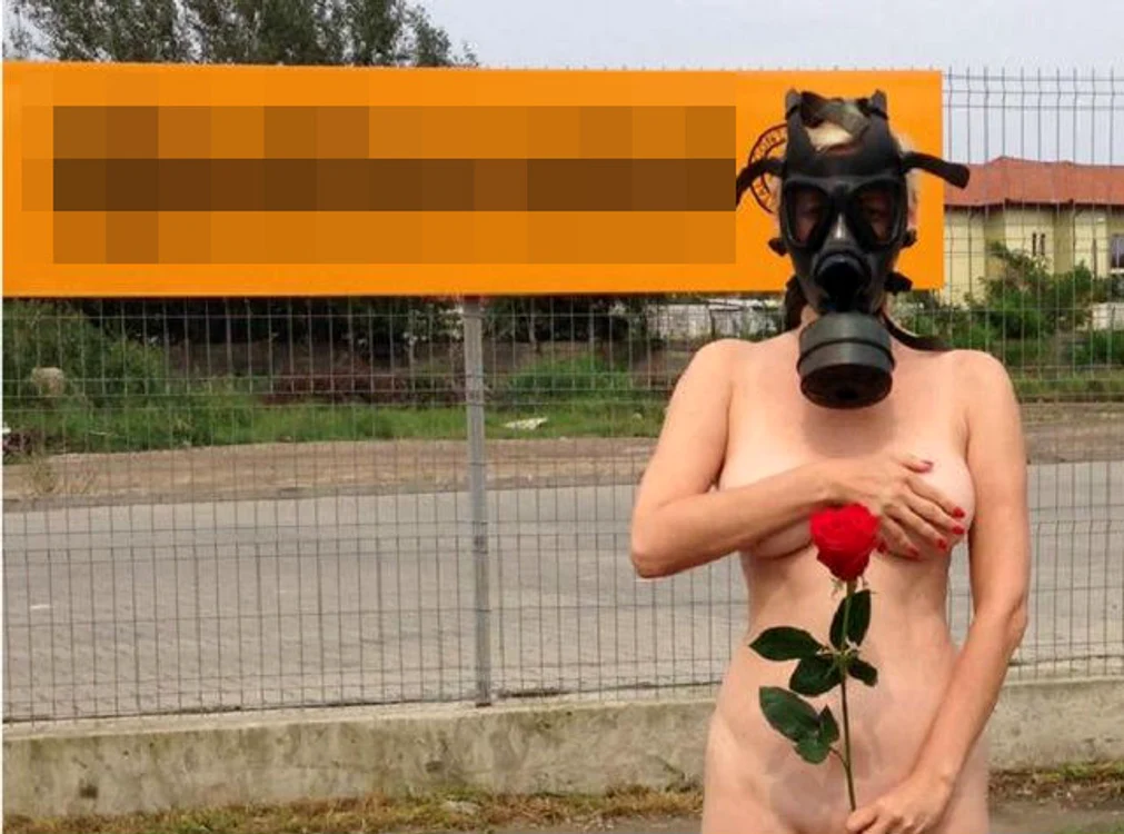 Dezbrăcată, cu mască de gaze pe faţă, pentru a atrage atenţia asupra mirosului emanat de fabrica de cauciucuri