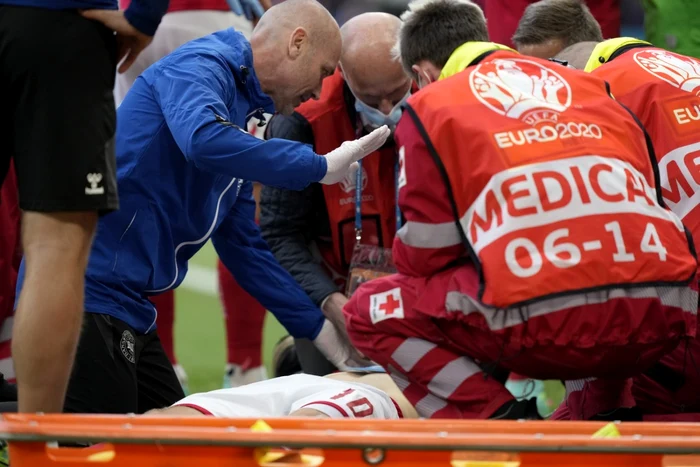 Medicul Martin Boesen, în albastru, îi oferă primul ajutor fotbalistului danez Christian Eriksen, prăbuşit pe teren Foto AFP