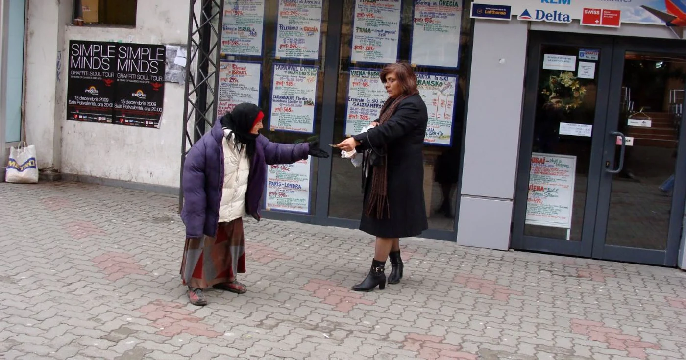 O bătrână care nu poate vorbi cerşeşte în apropierea magazinului Trivale