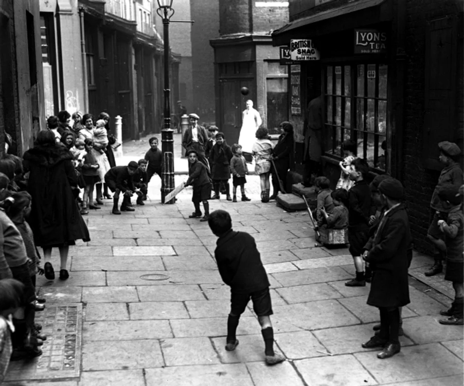 25 aprilie 1939: Copiii se joacă cricket pe o stradă din londra, terenul fiind improvizat între două felinare