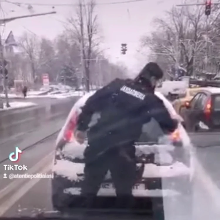 Momentul în care jandarmul îi curăţă luneta de zăpadă unui şofer   FOTO Facebook/Atenţie Poliţia Iaşi