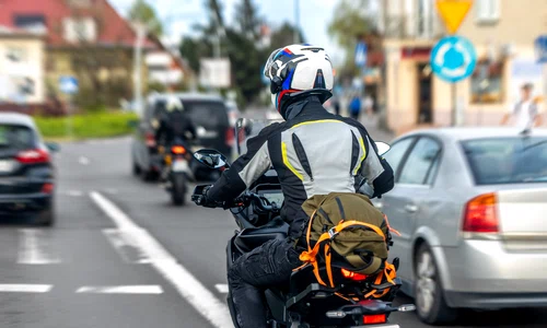 motorcyclist with backpack stopped city intersection rear view rider traffic jpg
