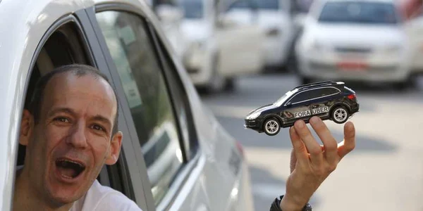 Un taximetrist cu o maşină de jucărie în mână protestează împotriva companiei Uber