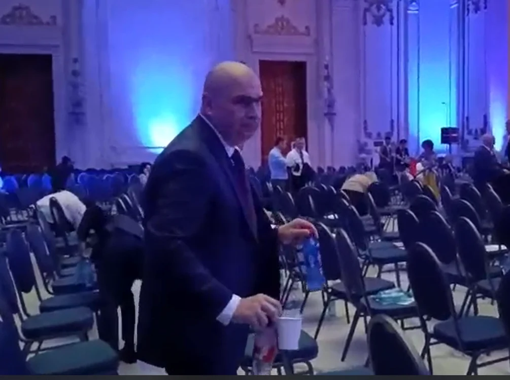 Premierul Ilie Bolojan strânge gunoaiele din sală FOTO: Captura video