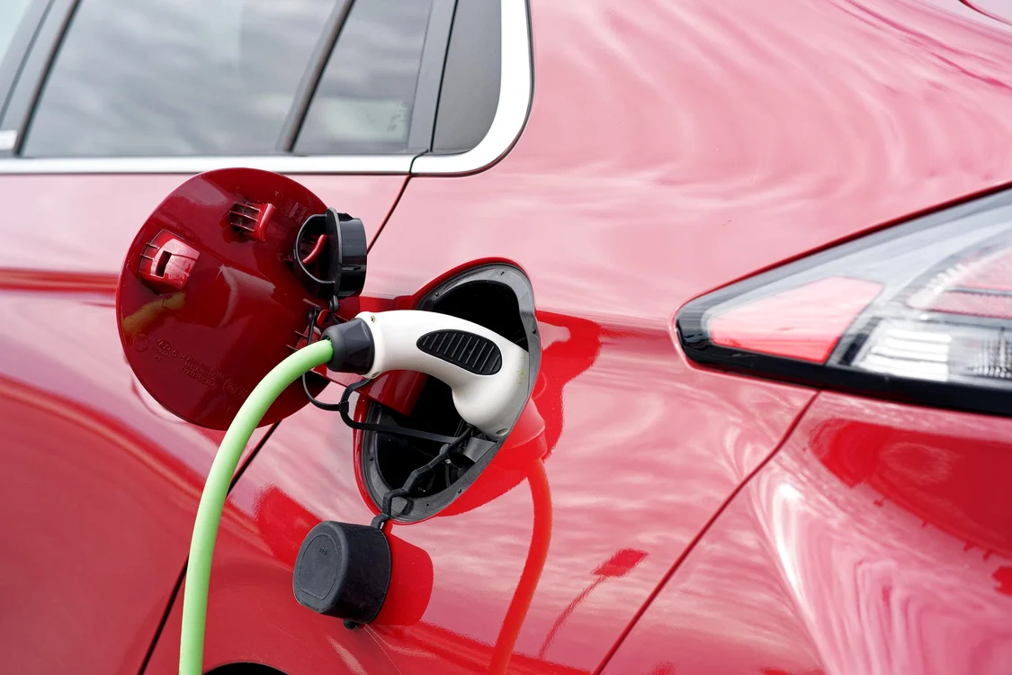O mașină electrică de culoare roție pusă la încărcat