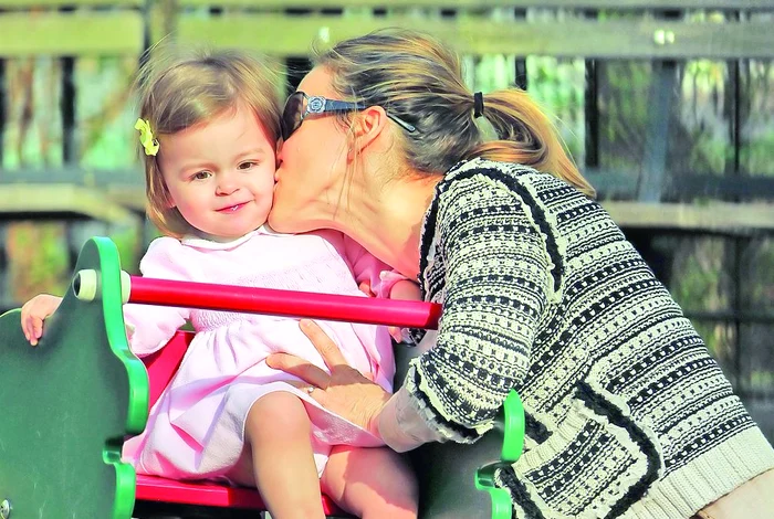 Actriţa o pupă drăgăstos pe una dintre gemene, care râde fericită...