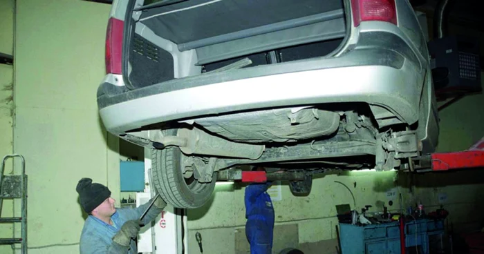 Un mecanic repară ceva la roata unei mașini