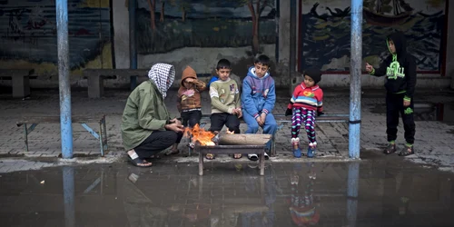 Un palestinian stă cu copii în jurul focului în curtea unei şcoli ONU în oraşul Gaza FOTO AP