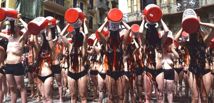 Protestatarii varsă pe ei găleţile pline cu lichid asemănător sângelui în semn de revoltă pentru luptele cu tauri de la Pamplona Foto peta.org.uk