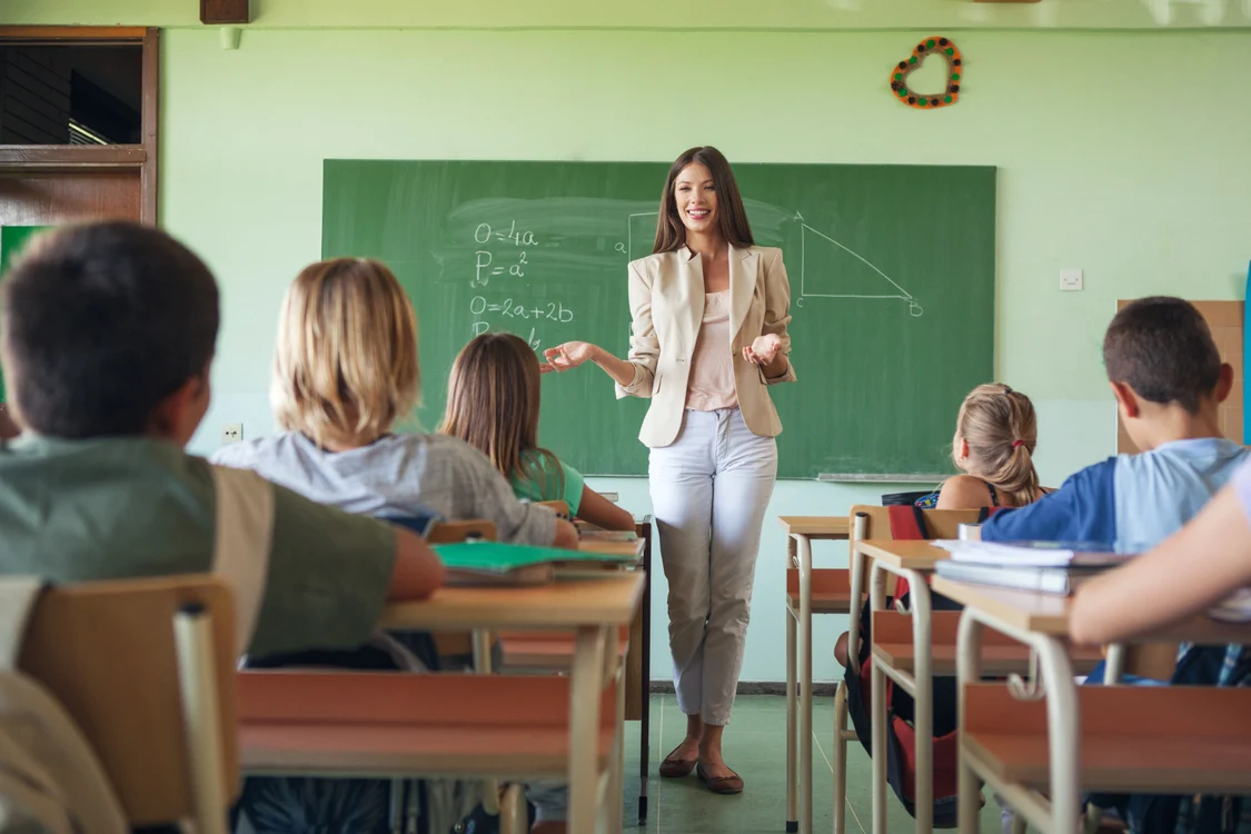 O profesoară tânără le predă elevilor în clasă