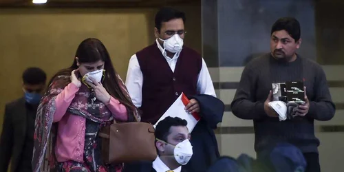 Oameni cu măşti de protecţie ies dintr-o companie chinezească din Islamabad FOTO AFP