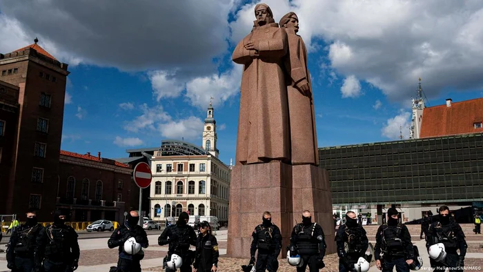 Ofițeri de poliție înconjoară un memorial sovietic care comemorează eliberarea Letoniei de naziști