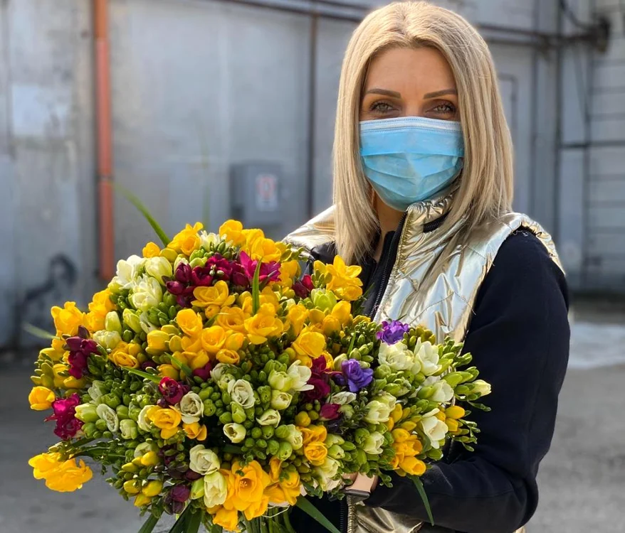
    Floristul Alina Neacșa poartă mască și mănuși atunci când aranjează buchetele  