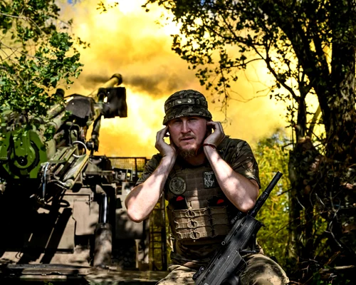 Un soldat ucrainean își acoperă urechile în timp ce militarii execută trageri cu un obuzier FOTO Profimedia 
