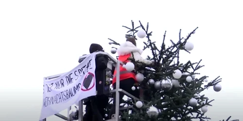 Două activiste pentru climă au tăiat cu fierăstrăul vârful pomului de Crăciun din faţa Porţii Brandenburg. Foto: Captură video YouTube