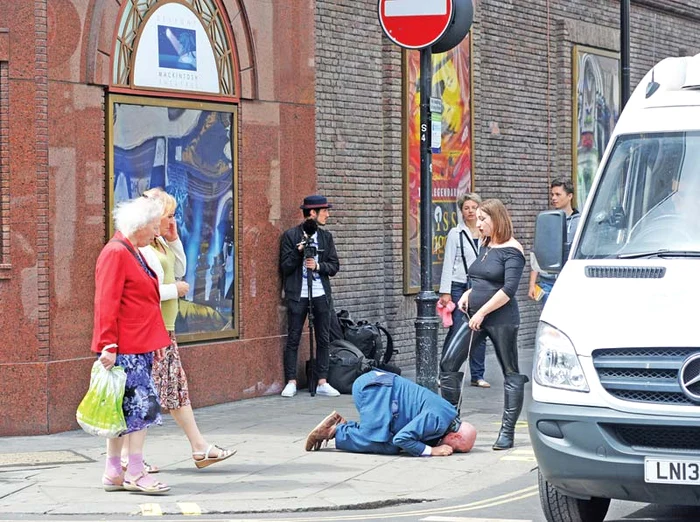 Unii trecători se îngrozesc când londonezul “curăţă” trotuarul cu limba