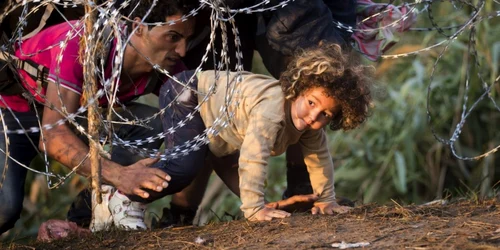 Refugiaţi trec prin gardul de sârmă forţând graniţa dintre Serbia şi Ungaria în Roszke Ungaria