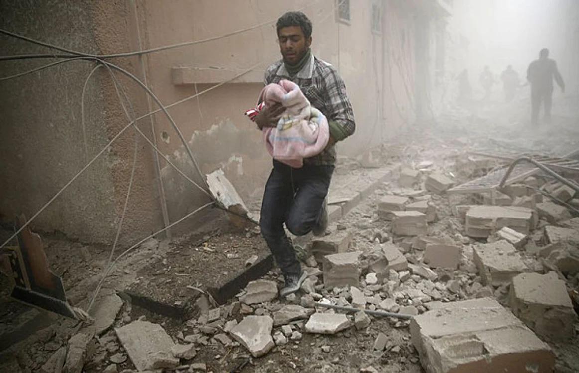 Un bărbat care un copil într-o pătură după o serie de bombardamente. FOTO AFP/ Getty Images