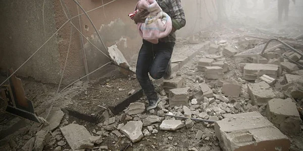Barbat care cara un copil intr-o patura dupa bombardamene FOTO AFP / Getty Images