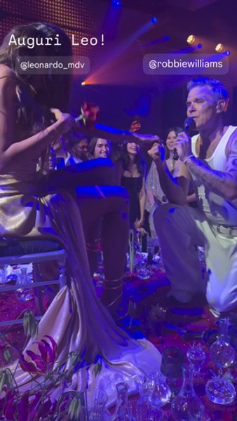 Robbie Williams, în genunchi în fața Mădălinei Ghenea. S-a urcat pe masă ca să cânte pentru ea