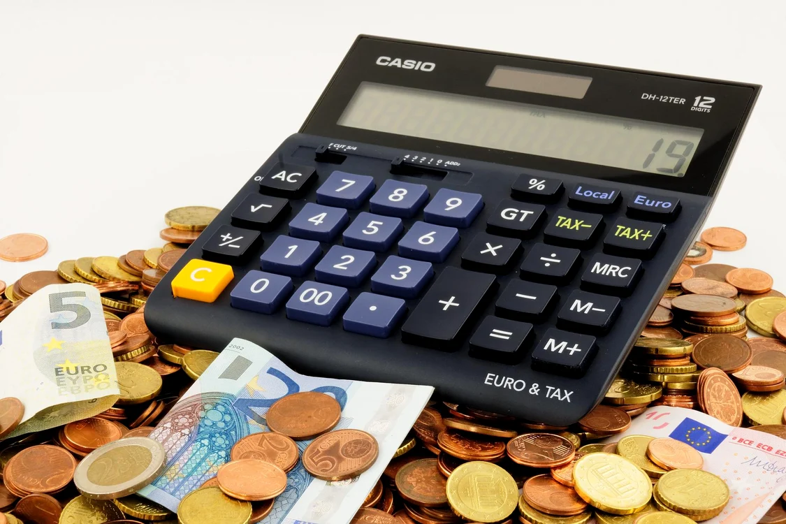 Monede și bancnote peste care este pus un calculator