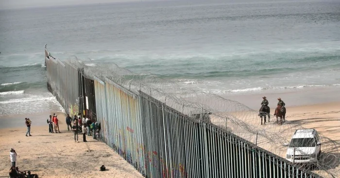 Oameni privesc grănicerii americani cum patrulează lângă zidul care separă Statele Unite de Mexic la ocenul Pacific în Tijuana Mexic FOTO Guliver / Getty Images / Scott Olson