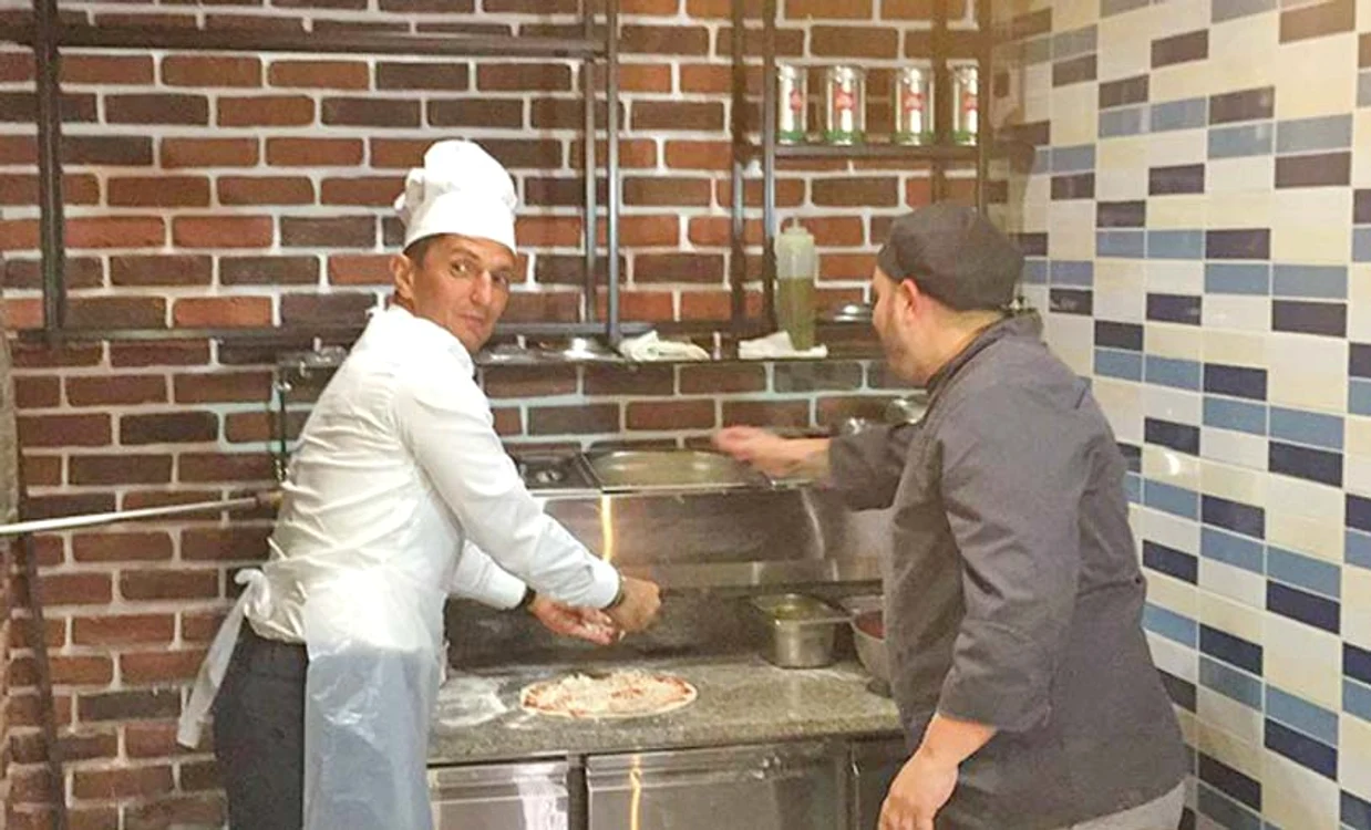 Antrenorul a pregătit  preparatele pentru  pizza și bruschete