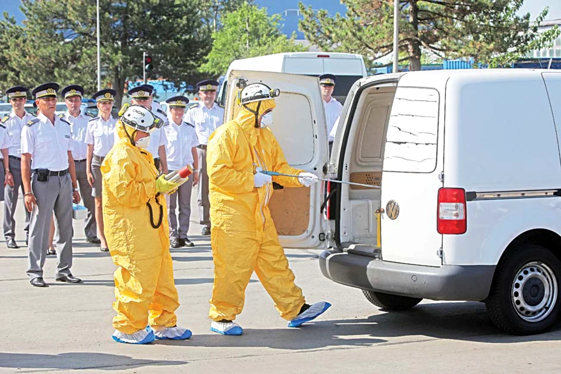 Oameni îmbrăcaţi în costume de protecţie preiau, cu atenţie sporită, coletele radioactive