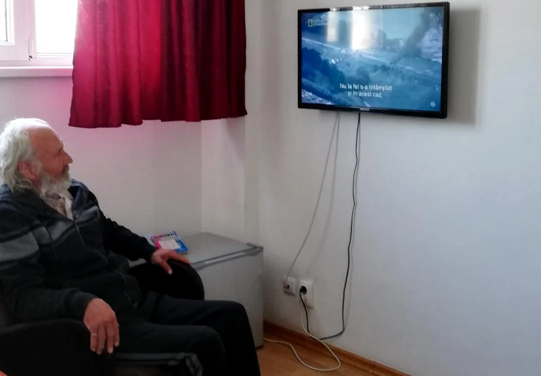 Domnul din imagine urmărește la televizor un documentar de pe National Geographic