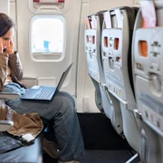 Femeie stă pe laptop în avion