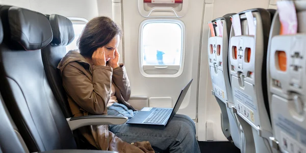 Femeie stă pe laptop în avion