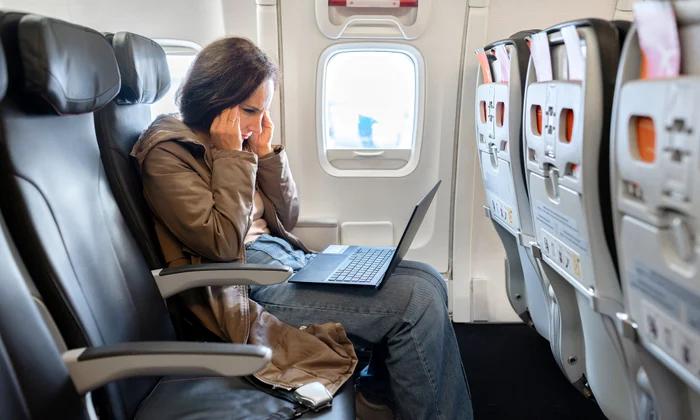 Femeie stă pe laptop în avion