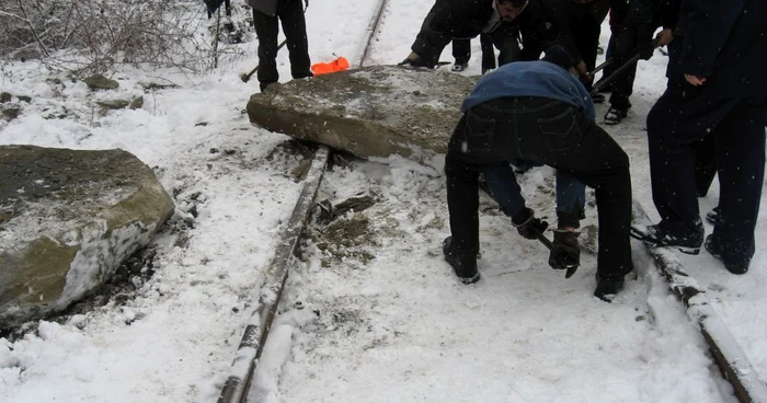 Muncitorii şi poliţiştii încercând să îndepărteze stânca de pe calea ferată
