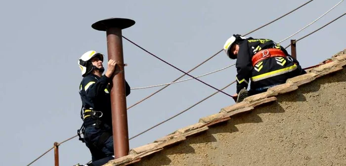 Un pompier fixează coşul de fum de pe Capela Sixtină FOTO Reuters