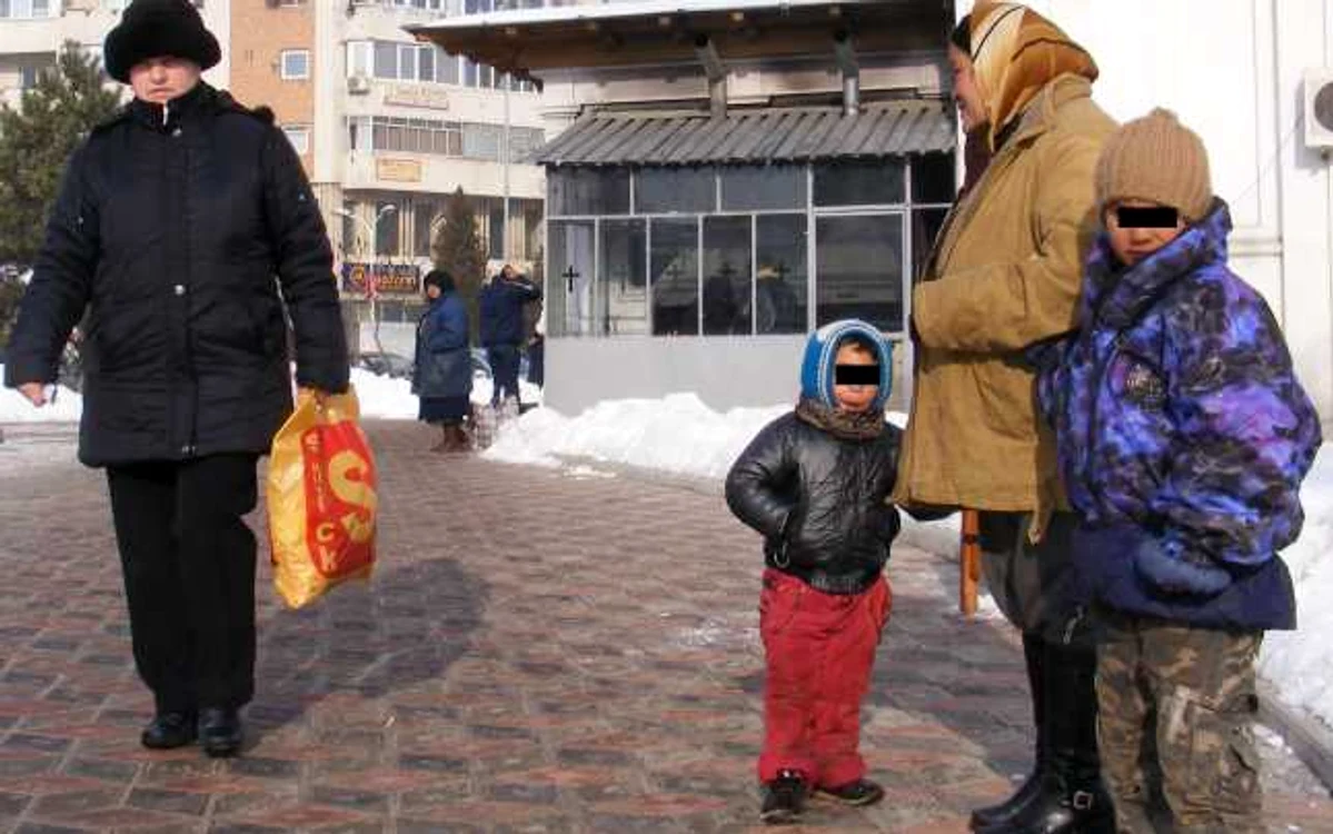 Doi ţănci murdari şi îmbrăcaţi sumar participă la cerşit cu mama lor